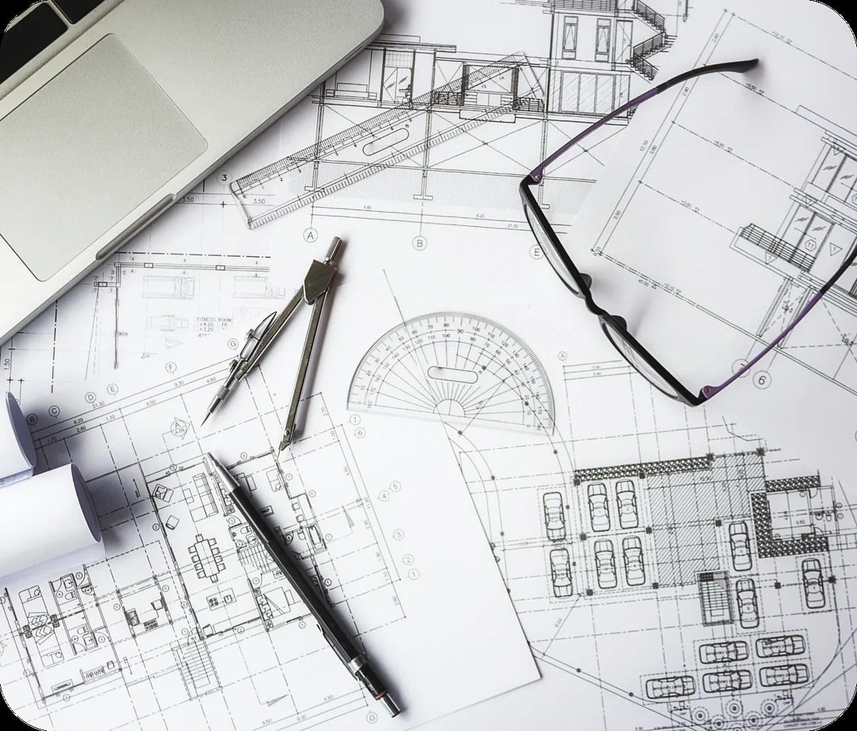 Construction plans, drafting tools and a laptop laid out on a desk