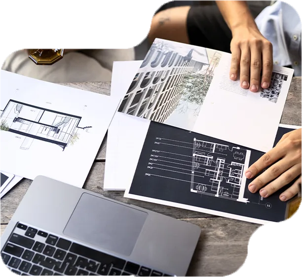 Two people reviewing construction drawings and floor plans at a desk